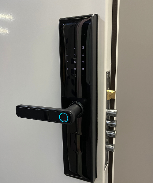 Fechadura digital preta instalada na porta branca de segurança